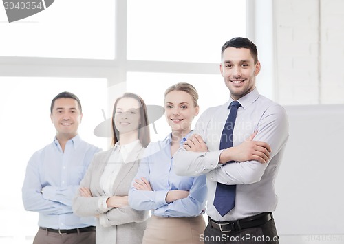 Image of smiling businessman in office with team on back