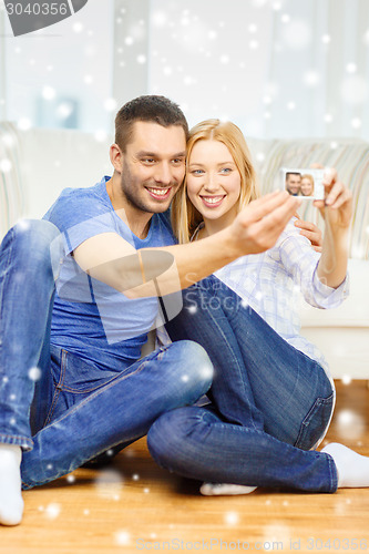 Image of smiling couple taking picture with digital camera