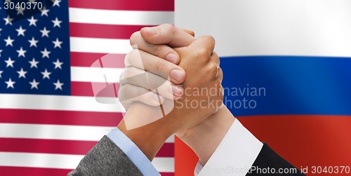 Image of hands armwrestling over american and russian flags