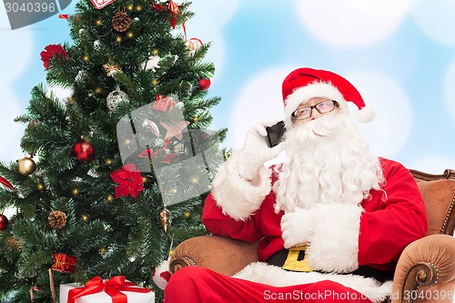 Image of santa claus with smartphone and christmas tree