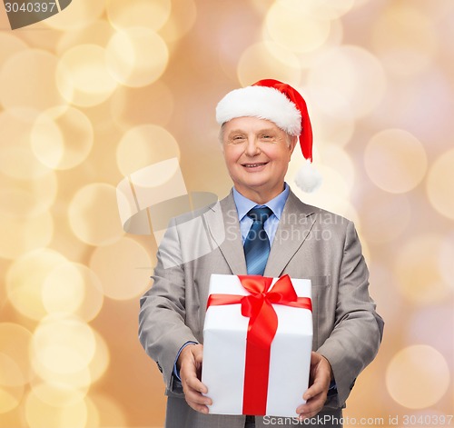 Image of smiling man in suit and santa helper hat with gift