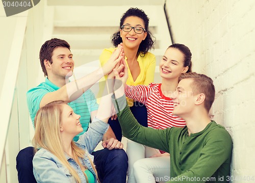 Image of smiling students making high five gesture sitting