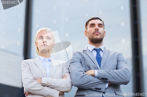 Image of serious businessmen standing over office building