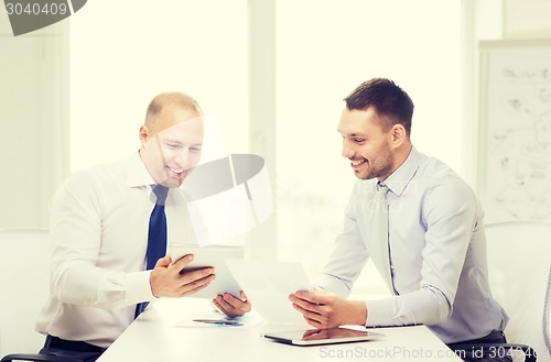 Image of two smiling businessmen with tablet pc in office