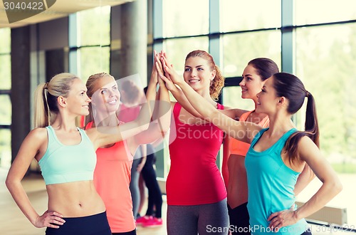 Image of group of women making high five gesture in gym