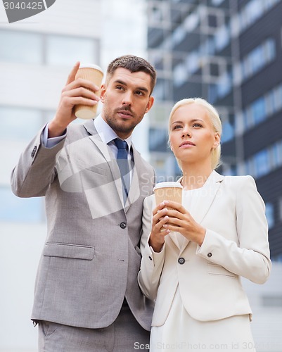 Image of serious businessmen with paper cups outdoors