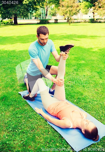 Image of serious couple stretching outdoors