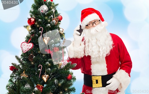 Image of santa claus with smartphone and christmas tree