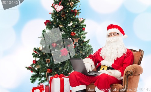 Image of man in costume of santa claus with laptop