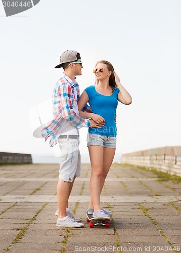 Image of smiling couple with skateboard outdoors