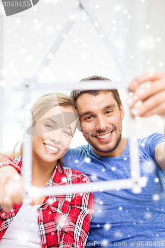 Image of smiling couple with house made of measuring tape