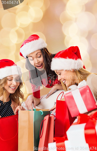 Image of smiling young women in santa hats with gifts