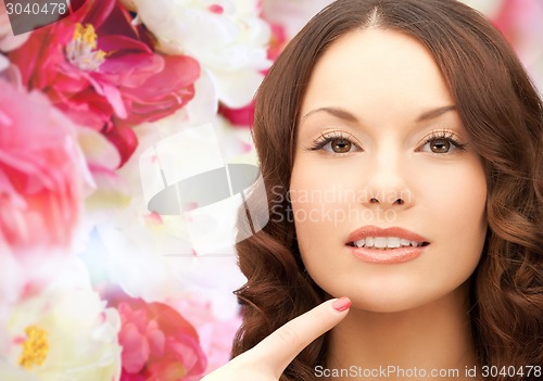 Image of beautiful young woman pointing finger to her chin