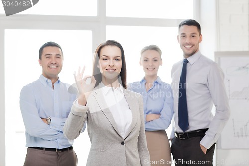 Image of smiling businesswoman showing ok-sign in office