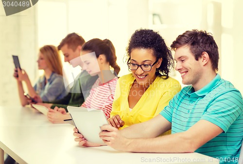 Image of smiling students looking at tablet pc at school