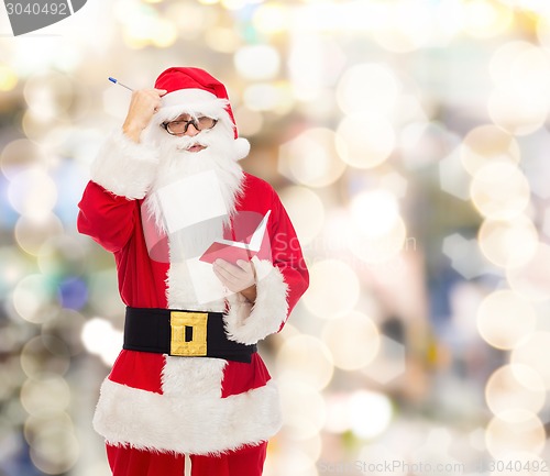 Image of man in costume of santa claus with notepad