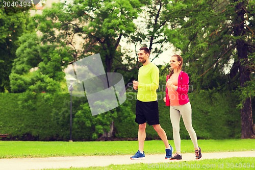 Image of smiling couple running outdoors