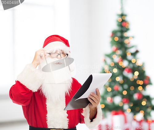 Image of man in costume of santa claus with notepad
