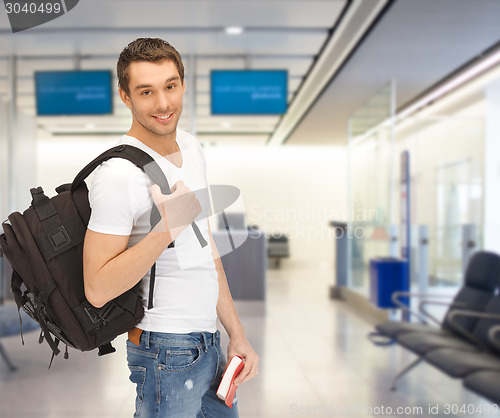 Image of smiling student with backpack and book at airport