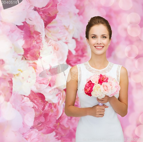 Image of smiling woman in white dress with bouquet of roses