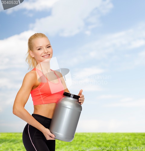 Image of smiling sporty woman with jar of protein