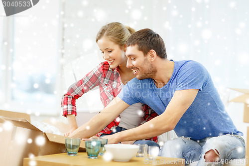 Image of smiling couple opening cardboard box with dishes
