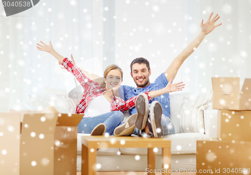 Image of smiling couple relaxing and waving hand at home