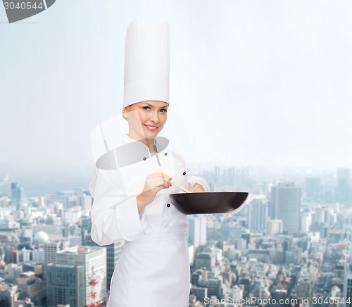 Image of smiling female chef with pan and spoon