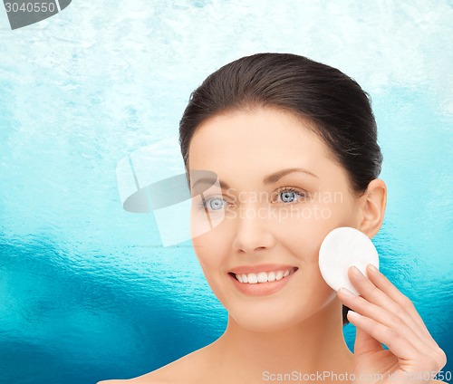 Image of smiling woman cleaning face skin with cotton pad