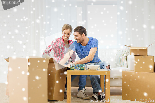 Image of smiling couple opening cardboard box with dishes