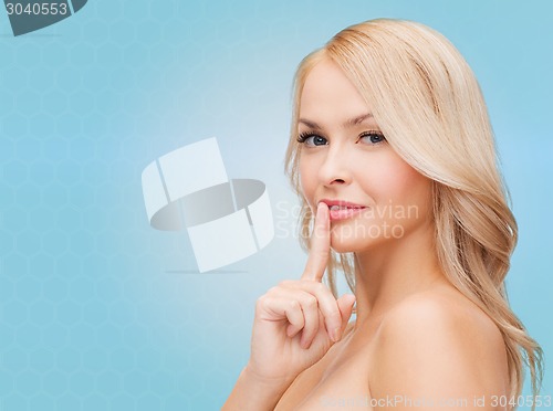 Image of beautiful young woman pointing finger to lips