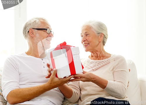 Image of happy senior couple with gift box at home