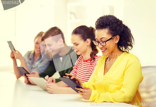 Image of smiling students looking at tablet pc at school