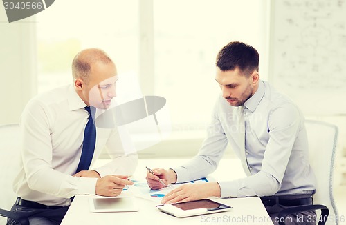 Image of two serious businessmen with tablet pc in office