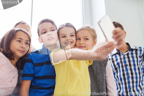 Image of group of school kids taking selfie with smartphone