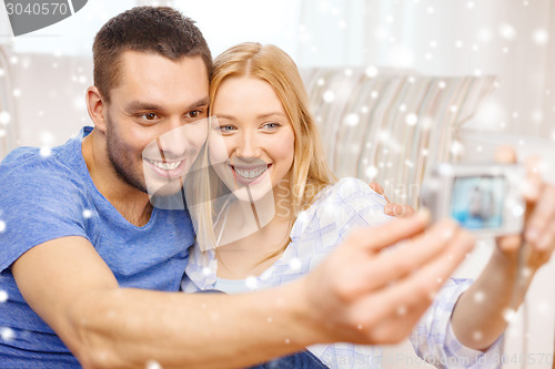 Image of smiling couple taking picture with digital camera