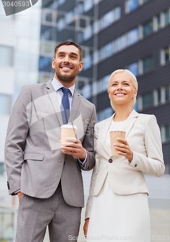 Image of smiling businessmen with paper cups outdoors