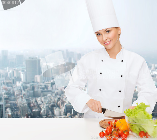 Image of smiling female chef chopping vegetables