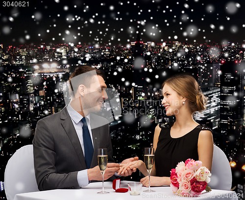 Image of smiling couple with red gift box at restaurant