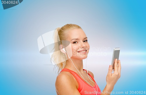 Image of smiling sporty woman with smartphone and earphones