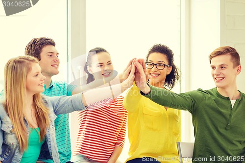 Image of smiling students making high five gesture sitting