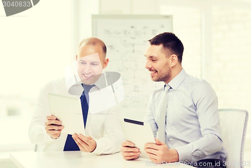 Image of two smiling businessmen with tablet pc in office