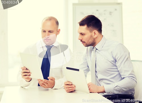 Image of two serious businessmen with tablet pc in office