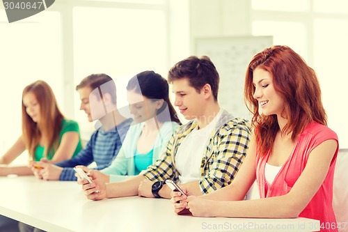 Image of smiling students with smartphones at school