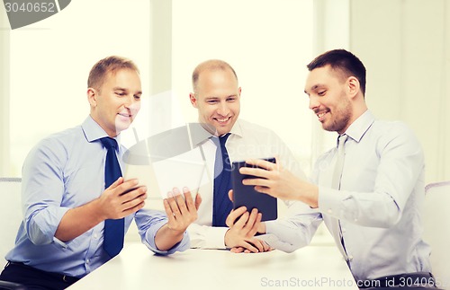 Image of three smiling businessmen with tablet pc in office