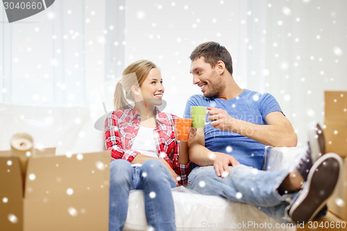 Image of smiling couple drinking tea or coffee at new home