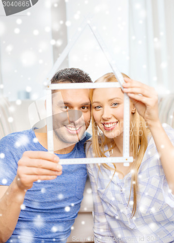 Image of smiling couple holding house model at home