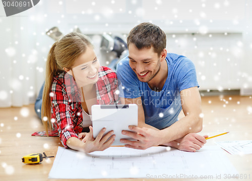 Image of smiling couple with  blueprint at home