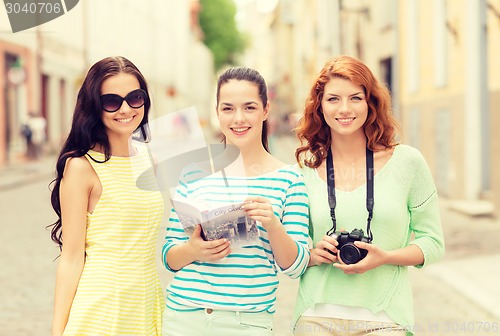 Image of smiling teenage girls with city guide and camera