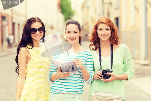 Image of smiling teenage girls with city guide and camera